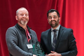 John McAlinden receiving the Helen Dowie Award from First Minister Humza Yousaf.